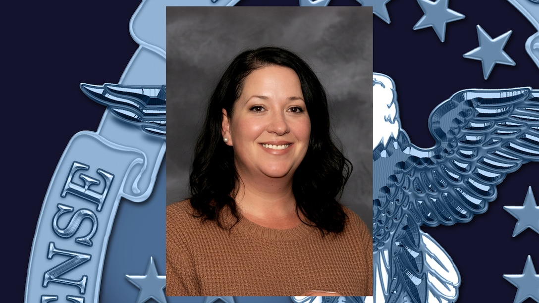 Headshot of woman with dark, shoulder-length hair wearing tan shirt