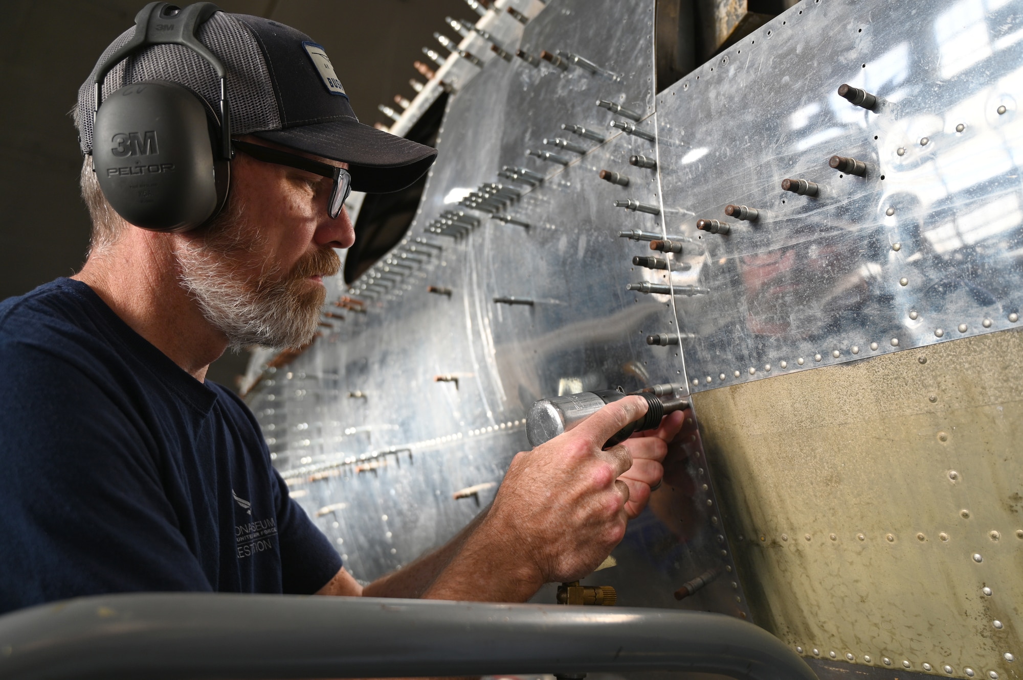 Restoration specialist Chad Vanhook applies rivets to an airplane.