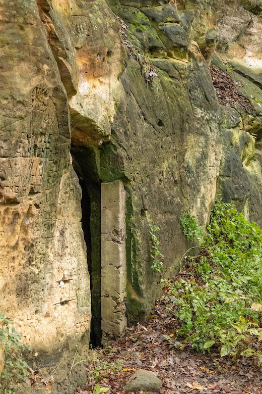 Brown rock formation with green and brown vegetation to the right.