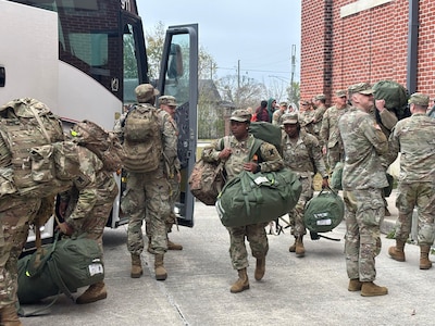 Soldiers assigned to A Battery, 1st Battalion, 141st Field Artillery Regiment, 256th Infantry Brigade Combat Team, load their gear and board buses following a departure ceremony at the 1-141st Field Artillery Battalion Armory on Jackson Barracks, Dec. 14, 2025.