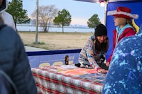 Jaylee Schmidt, 811th Force Support Squadron marketing coordinator, speaks with a military family during the Winterfest celebration at Joint Base Anacostia-Bolling, Washington, D.C., Dec. 6, 2025. The 811th FSS hosted the event in support of their mission to provide family support to Airmen in the National Capital Region. (U.S. Air Force photo by Airman 1st Class Shanel Toussaint)