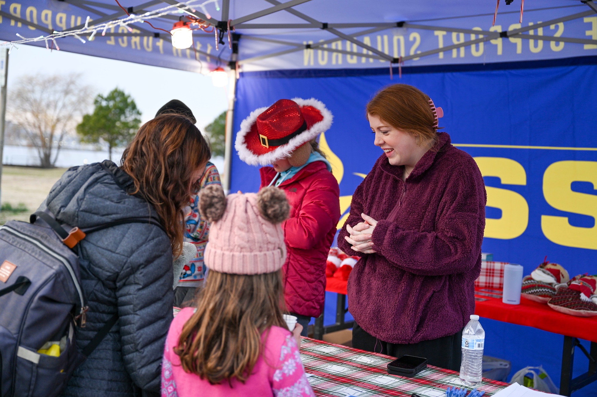 Jaylee Schmidt, 811th Force Support Squadron marketing coordinator, speaks with a military family during the Winterfest celebration at Joint Base Anacostia-Bolling, Washington, D.C., Dec. 6, 2025. The 811th FSS hosted the event in support of their mission to provide family support to Airmen in the National Capital Region. (U.S. Air Force photo by Airman 1st Class Shanel Toussaint)