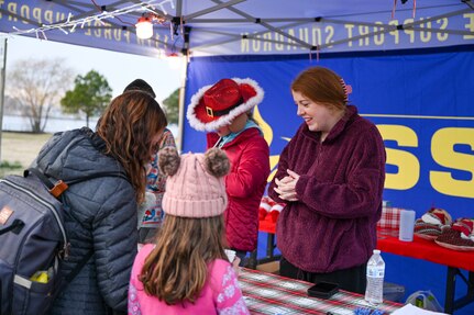 Jaylee Schmidt, 811th Force Support Squadron marketing coordinator, speaks with a military family during the Winterfest celebration at Joint Base Anacostia-Bolling, Washington, D.C., Dec. 6, 2025. The 811th FSS hosted the event in support of their mission to provide family support to Airmen in the National Capital Region. (U.S. Air Force photo by Airman 1st Class Shanel Toussaint)