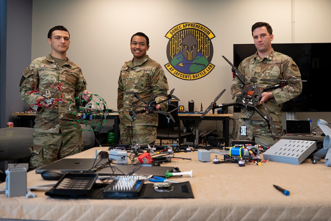 U.S. Air Force Airman 1st Class Kelson Whitten, Airman 1st Class Keelam Graham and Airman 1st Class Braden Schwartz, 9th Air Force (Air Forces Central) Battle Lab software engineers, display several drone systems Nov. 7, 2025, at Shaw Air Force Base, South Carolina. The AFCENT Battle Lab is constructing small, unmanned aircraft systems to be used in a variety of applications throughout the U.S. Central Command area of responsibility. (U.S. Air Force photo by Tech. Sgt. Aaron J. Jenne)
