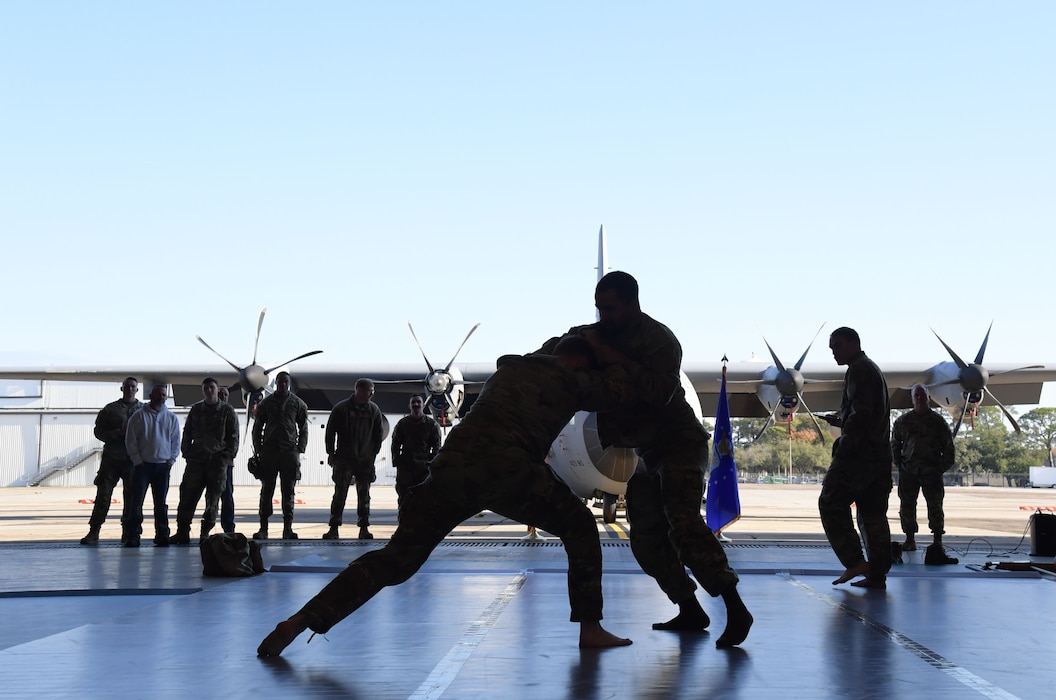 Two men wearing military uniforms wrestle.