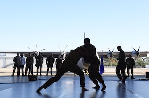 Two men wearing military uniforms wrestle.