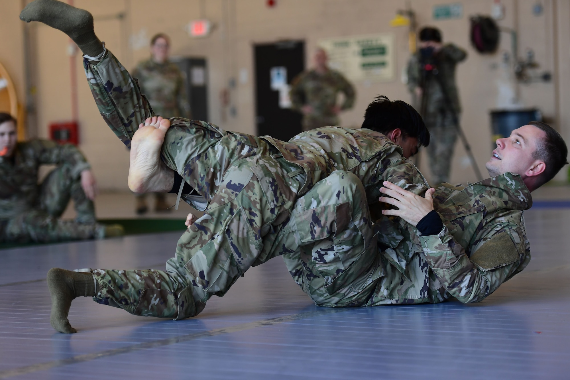 Two men wearing military uniform wrestle.