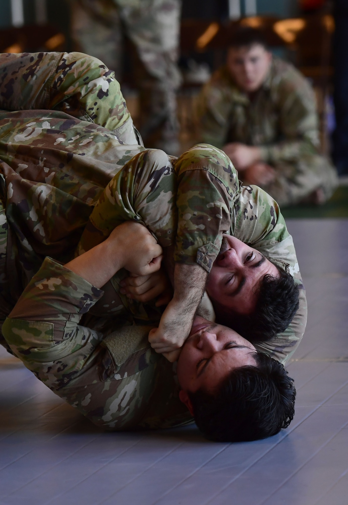 Two men wearing military uniforms wrestle.