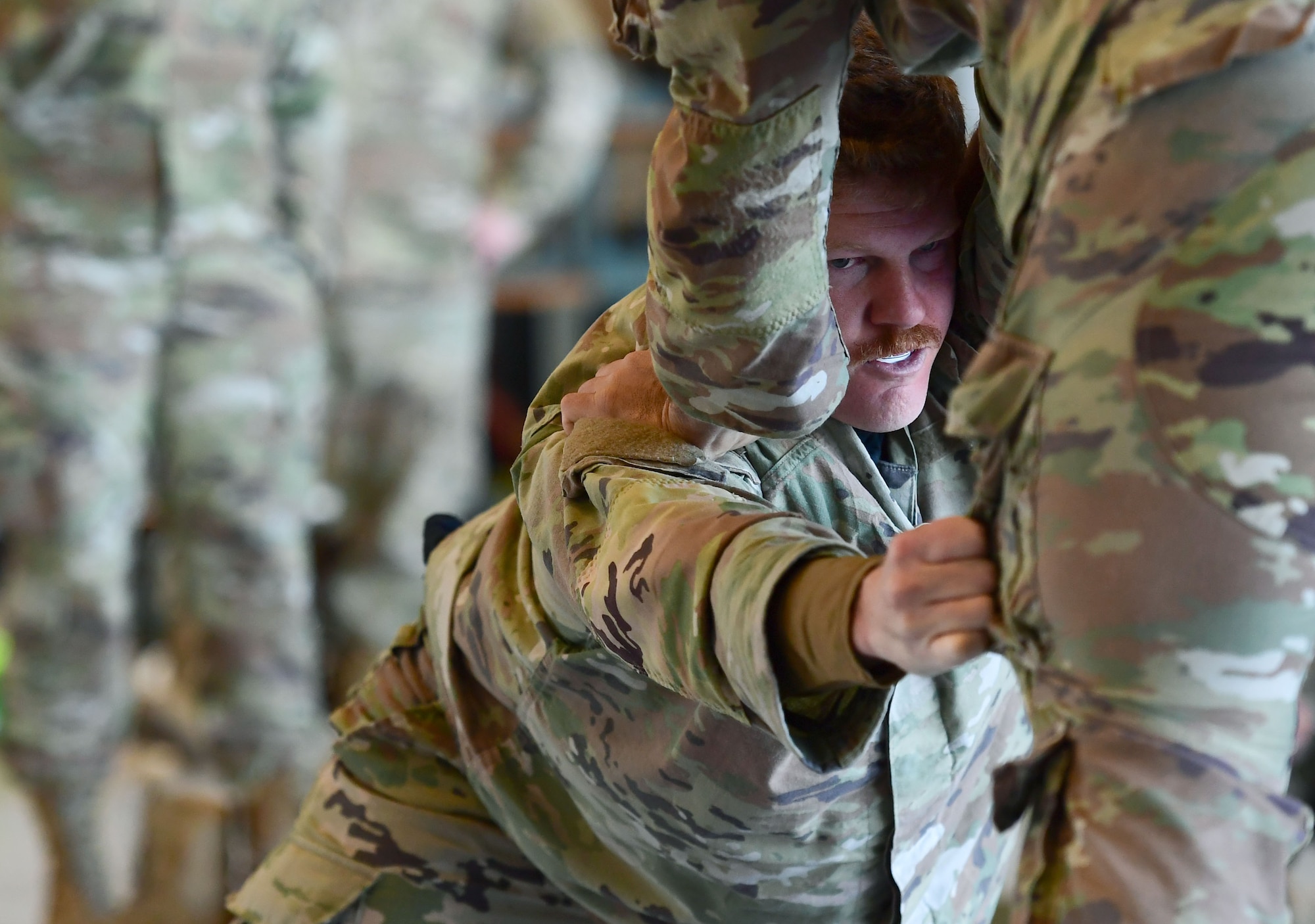 Two men wearing military uniforms wrestle.