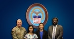 Four people are standing in front of a blue background with the Agency seal shown.