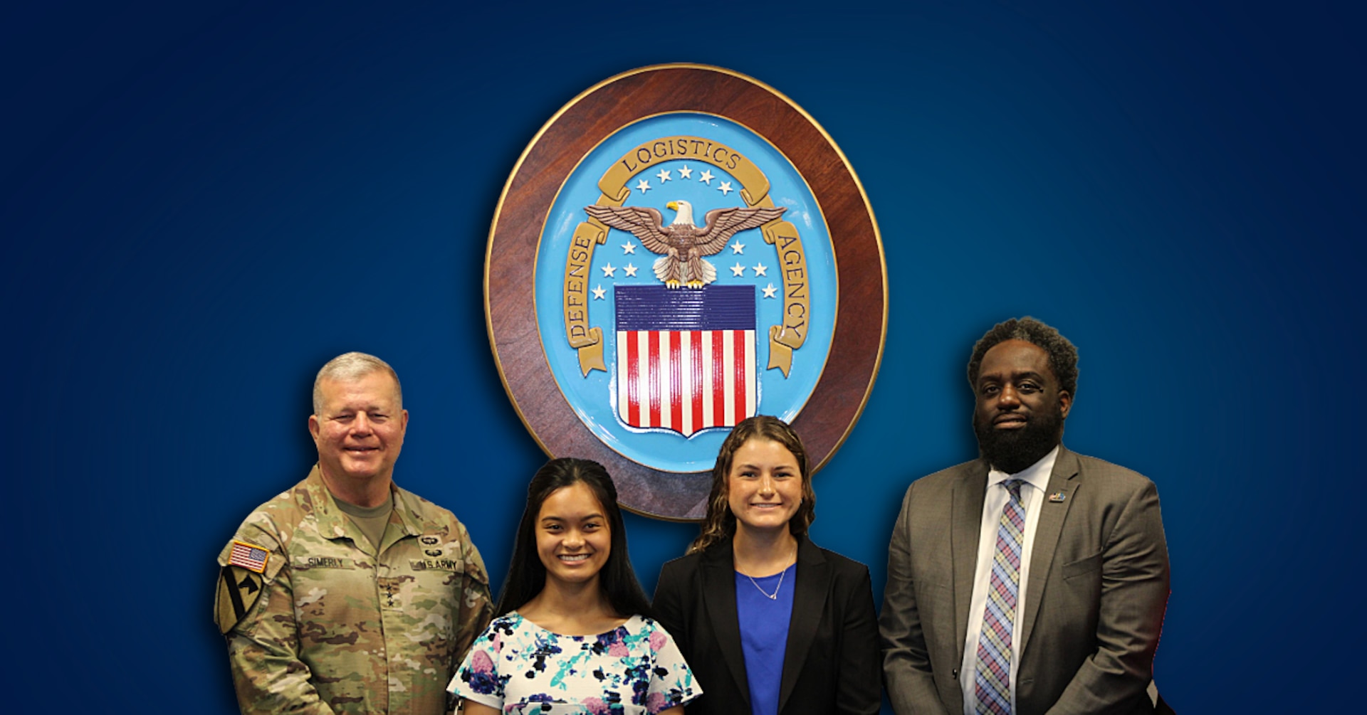 Four people are standing in front of a blue background with the Agency seal shown.