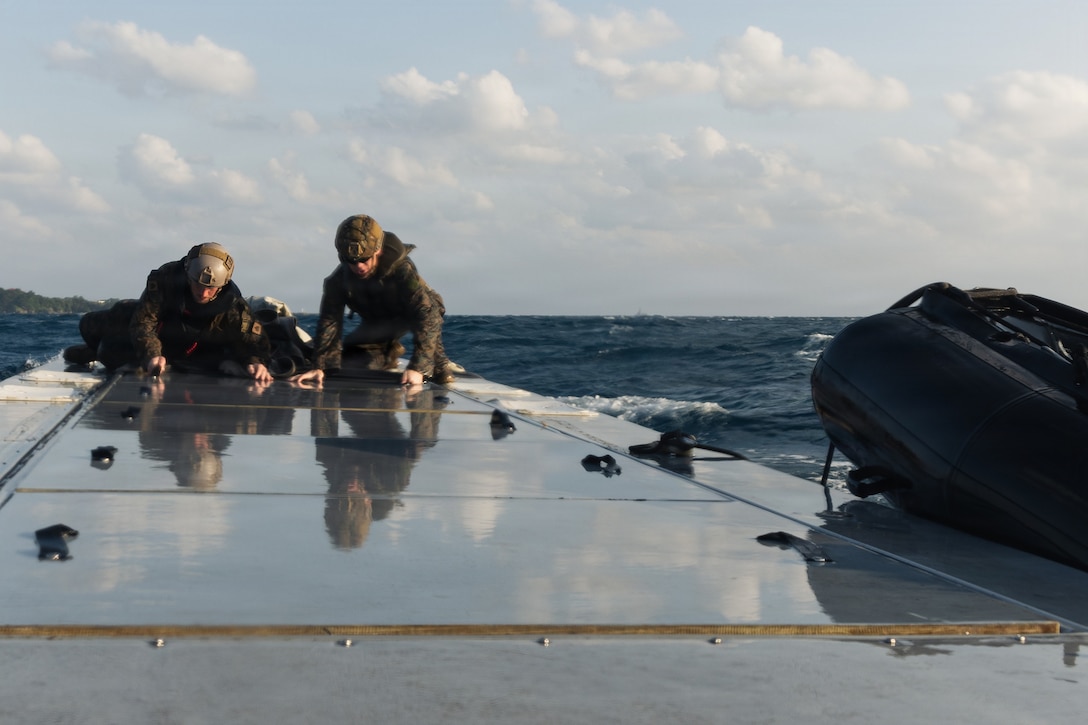 U.S. Marines with India Company, Battalion Landing Team 3rd Battalion, 1st Marine Regiment, 31st Marine Expeditionary Unit, conduct an at sea resupply drill with supplies from an autonomous low-profile vessel during unmanned surface vessel training operations as part of MEU Exercise at White Beach Naval Facility, Okinawa, Japan on Dec. 3, 2025. The ALPV has the ability to deliver multiple variations of supplies and equipment through contested maritime terrain. The 31st MEU, the Marine Corps’ only continuously forward deployed MEU, provides a flexible and lethal force, ready to perform a wide range of military operations as the premiere crisis response force in the Indo-Pacific region. (U.S. Marine Corps photo by Sgt. Alora Finigan)