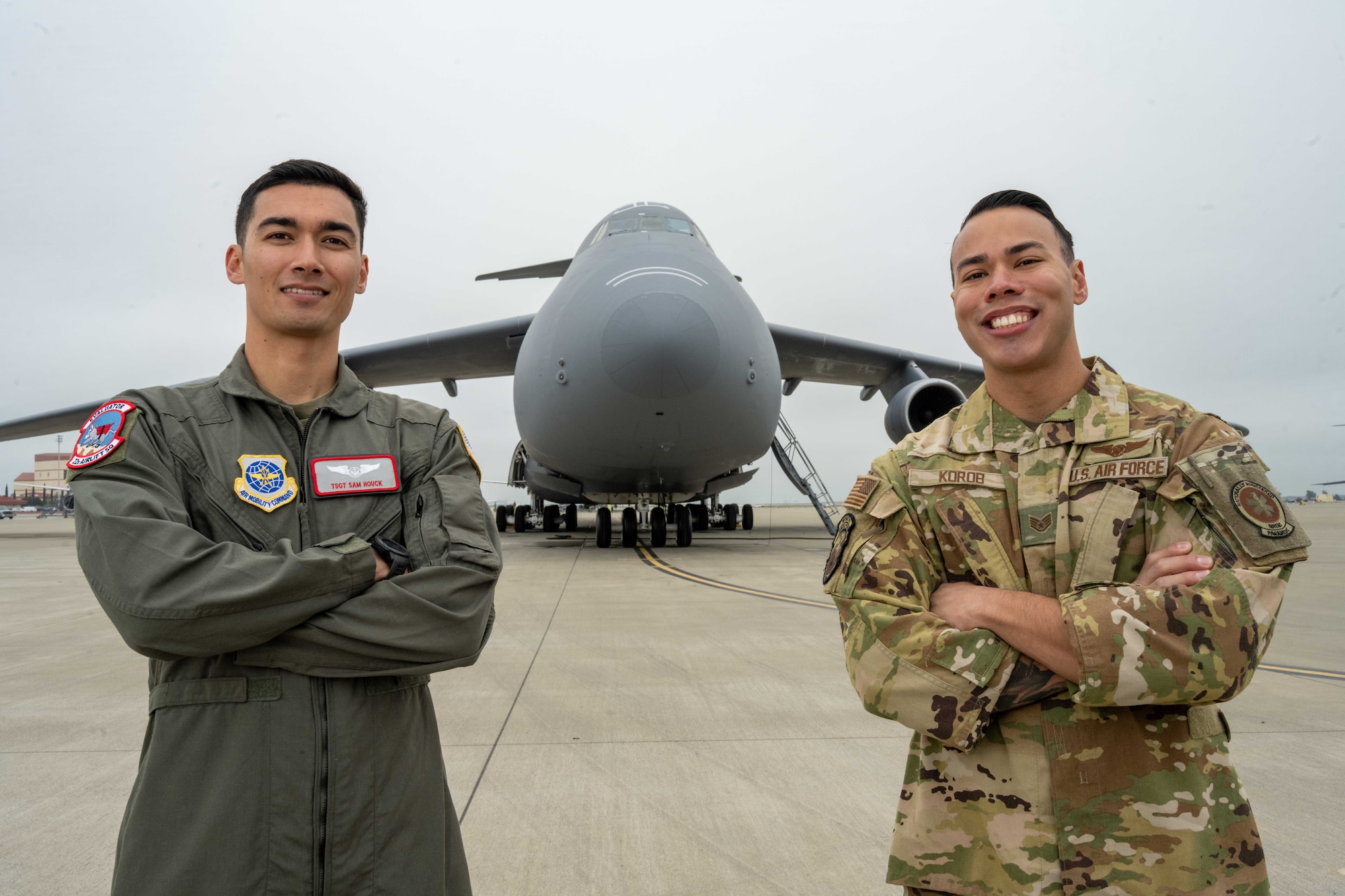 U.S. Air Force crewmen stand in front of C-5 Galaxy with arms crossed.