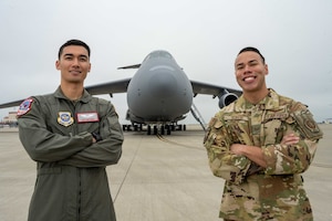 U.S. Air Force crewmen stand in front of C-5 Galaxy with arms crossed.