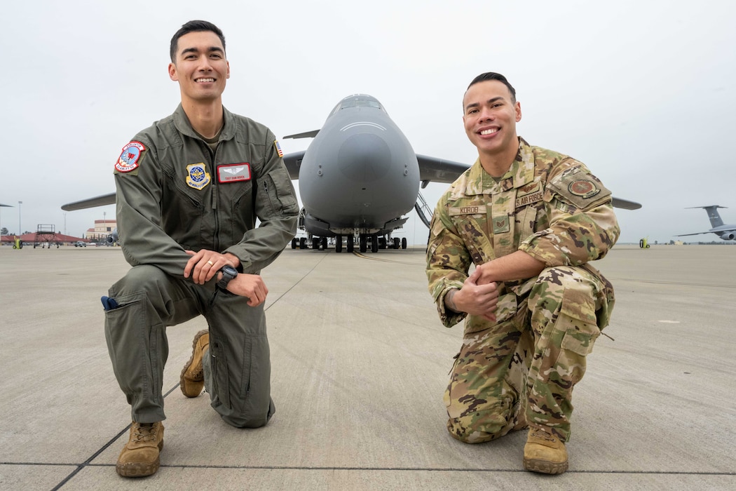 U.S. Air Force crewman take a knee in front of C-5 Galaxy with arms crossed.