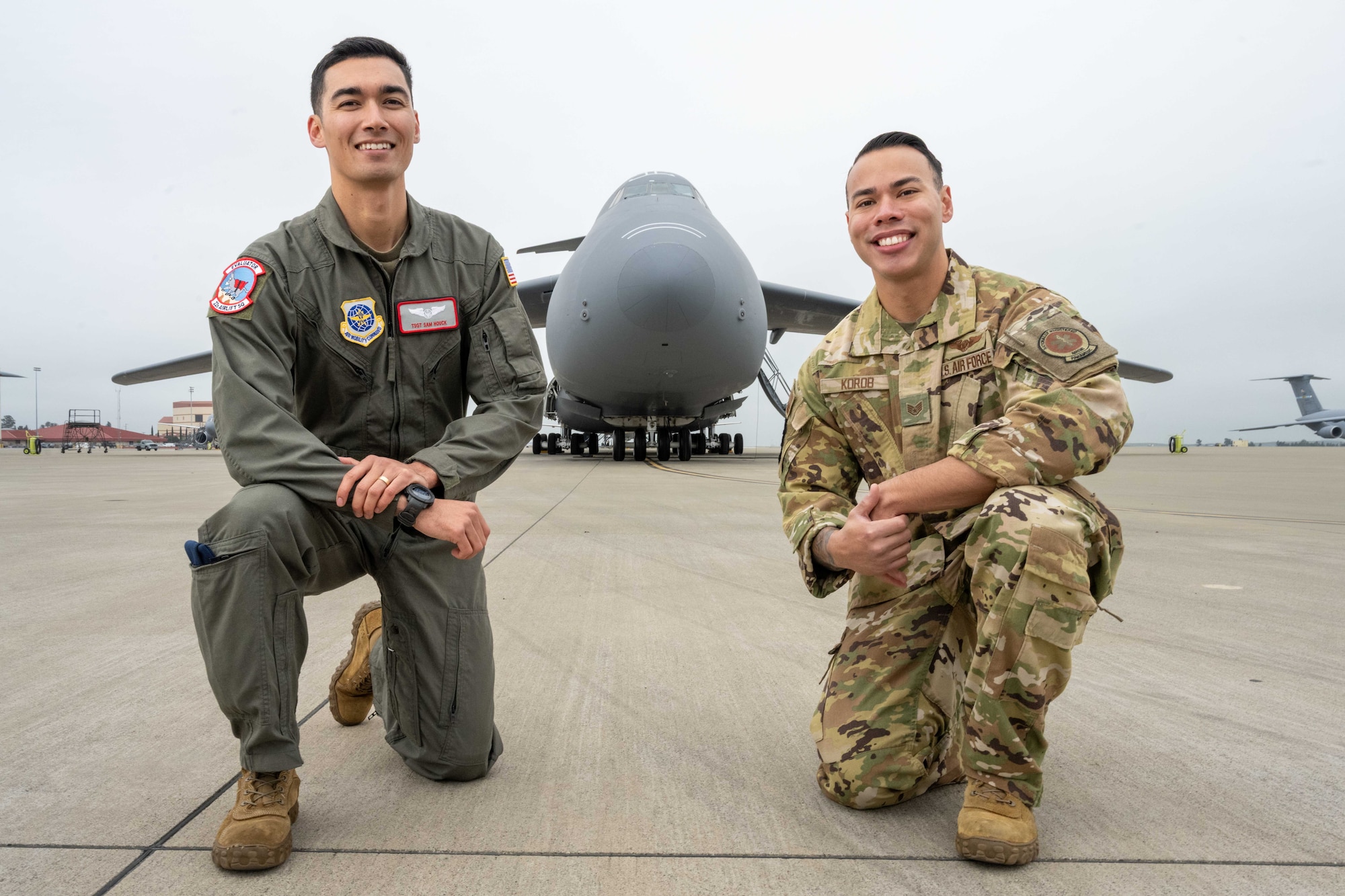 U.S. Air Force crewman take a knee in front of C-5 Galaxy with arms crossed.