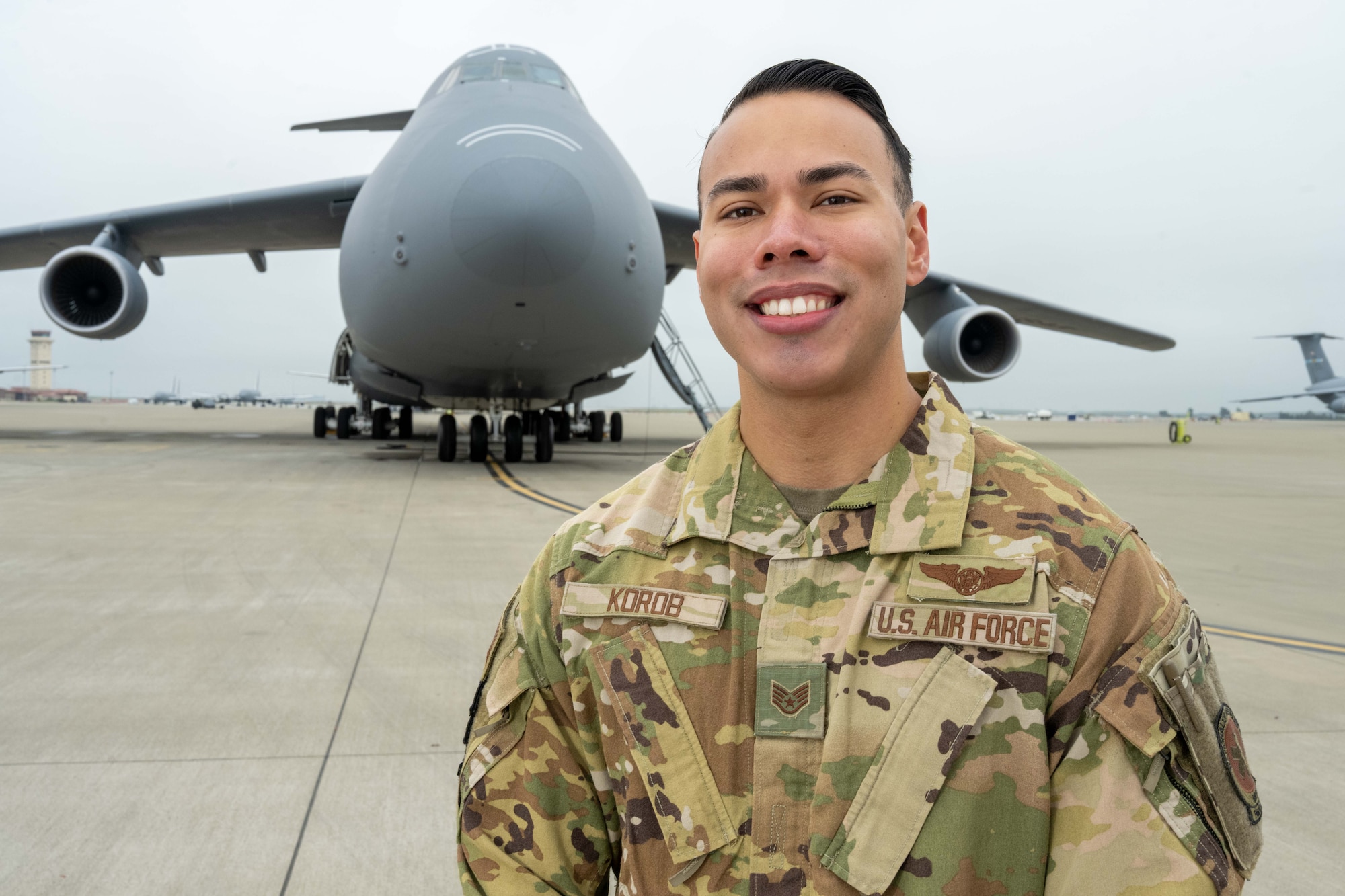 U.S. Air Force crewman stands in front of C-5 Galaxy with arms crossed.