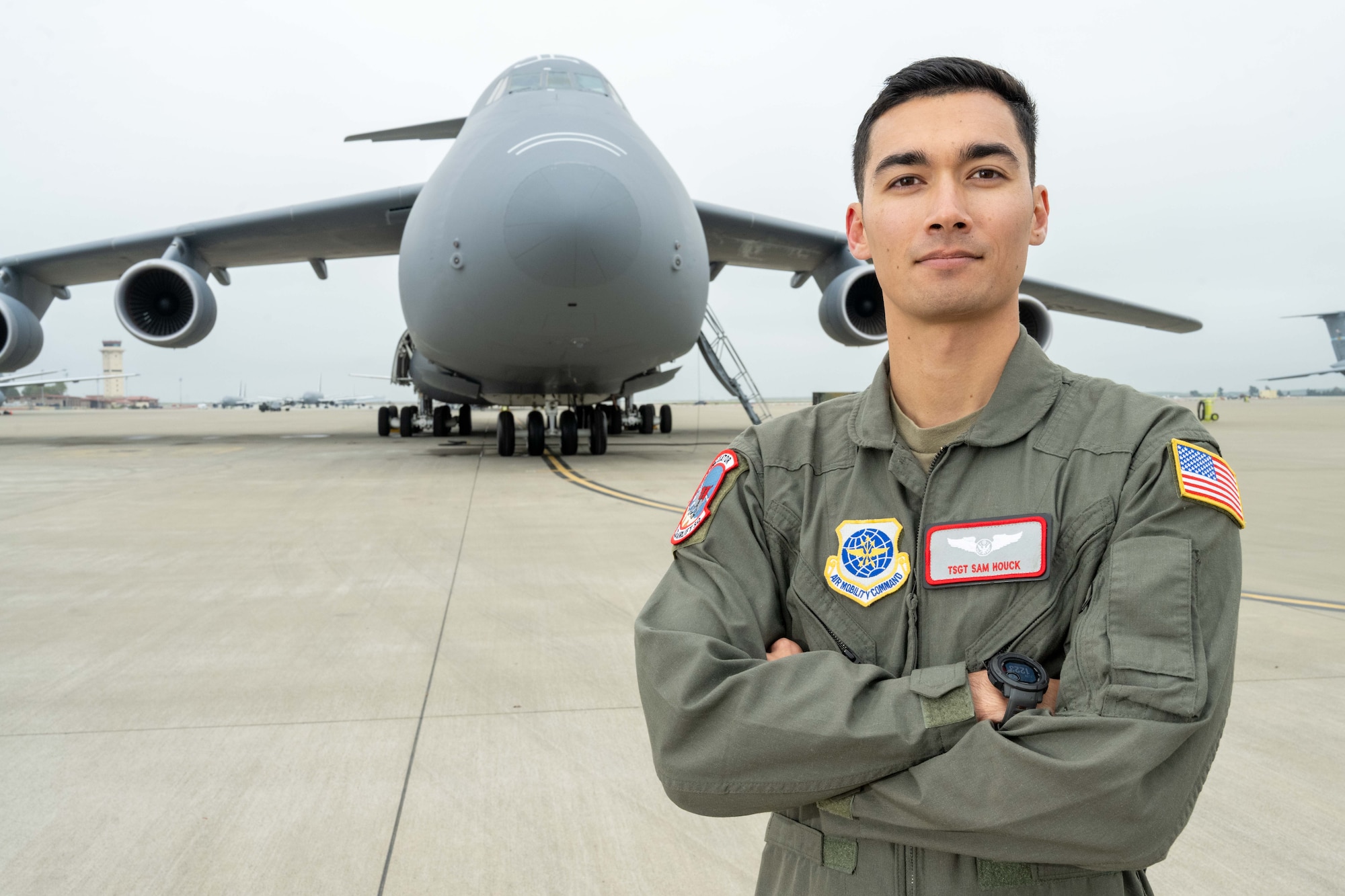 U.S. Air Force crewman stands in front of C-5 Galaxy with arms crossed.