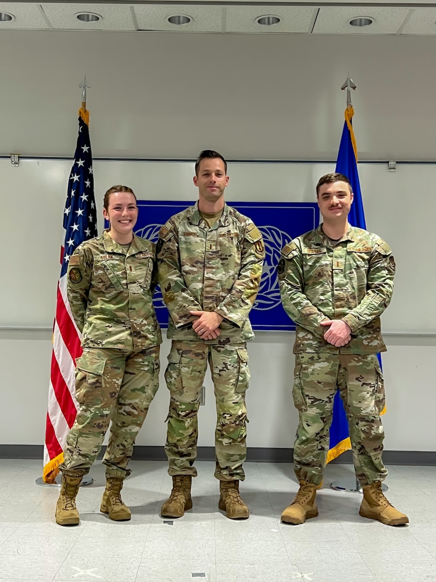 Three military members in uniform pose for a photo