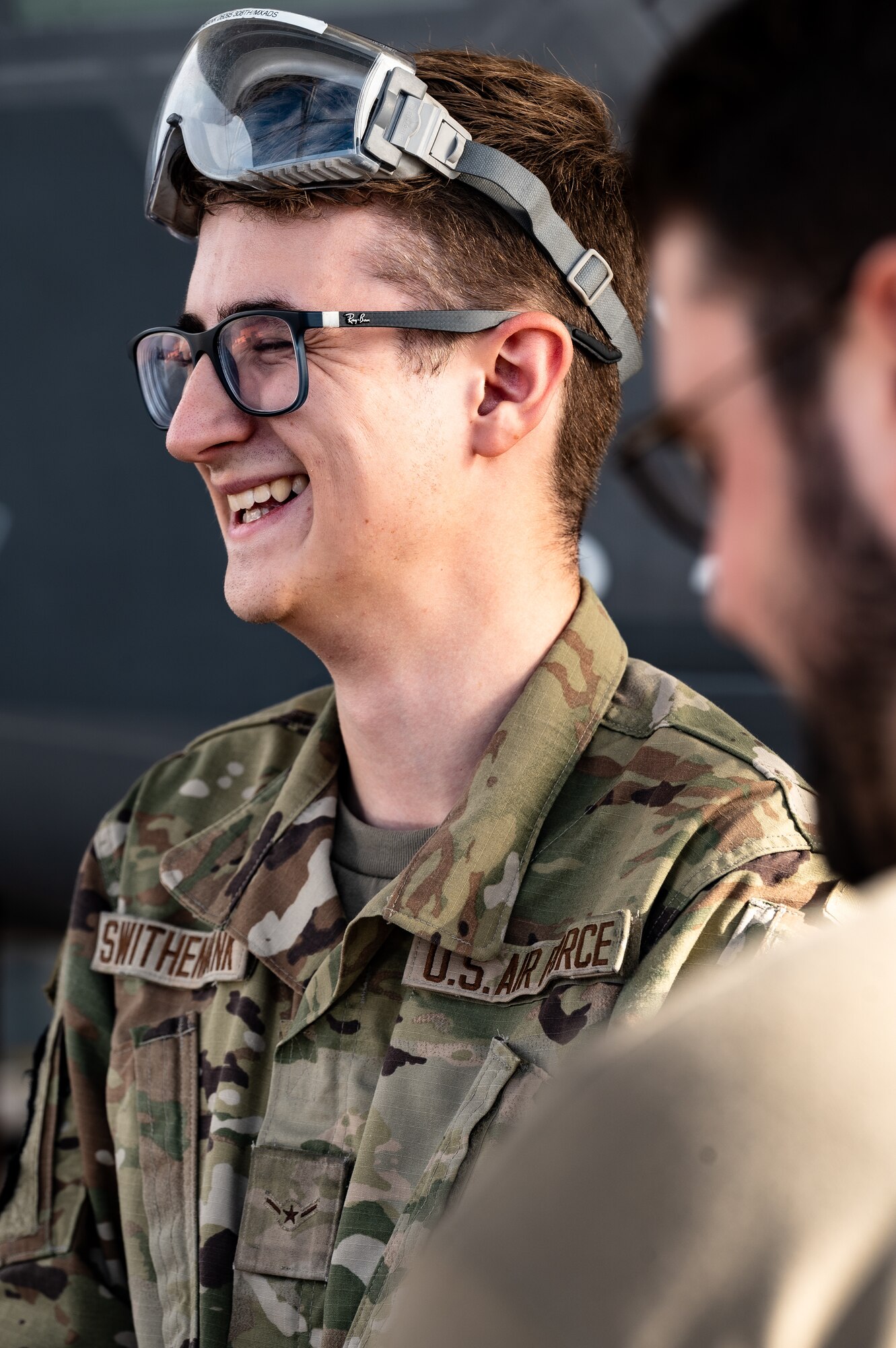 U.S. Air Force Airman Wilson Swithenbank, 308th Aircraft Maintenance Unit F-35 integrated avionics technician apprentice, smiles with wingmen while performing maintenance on an F-35A Lightning II