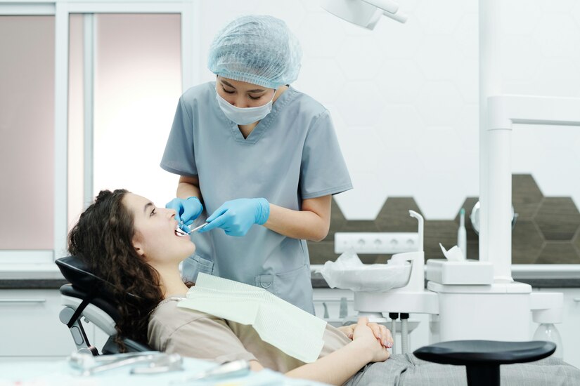 Dentist uses dental equipment on a patient in a white room