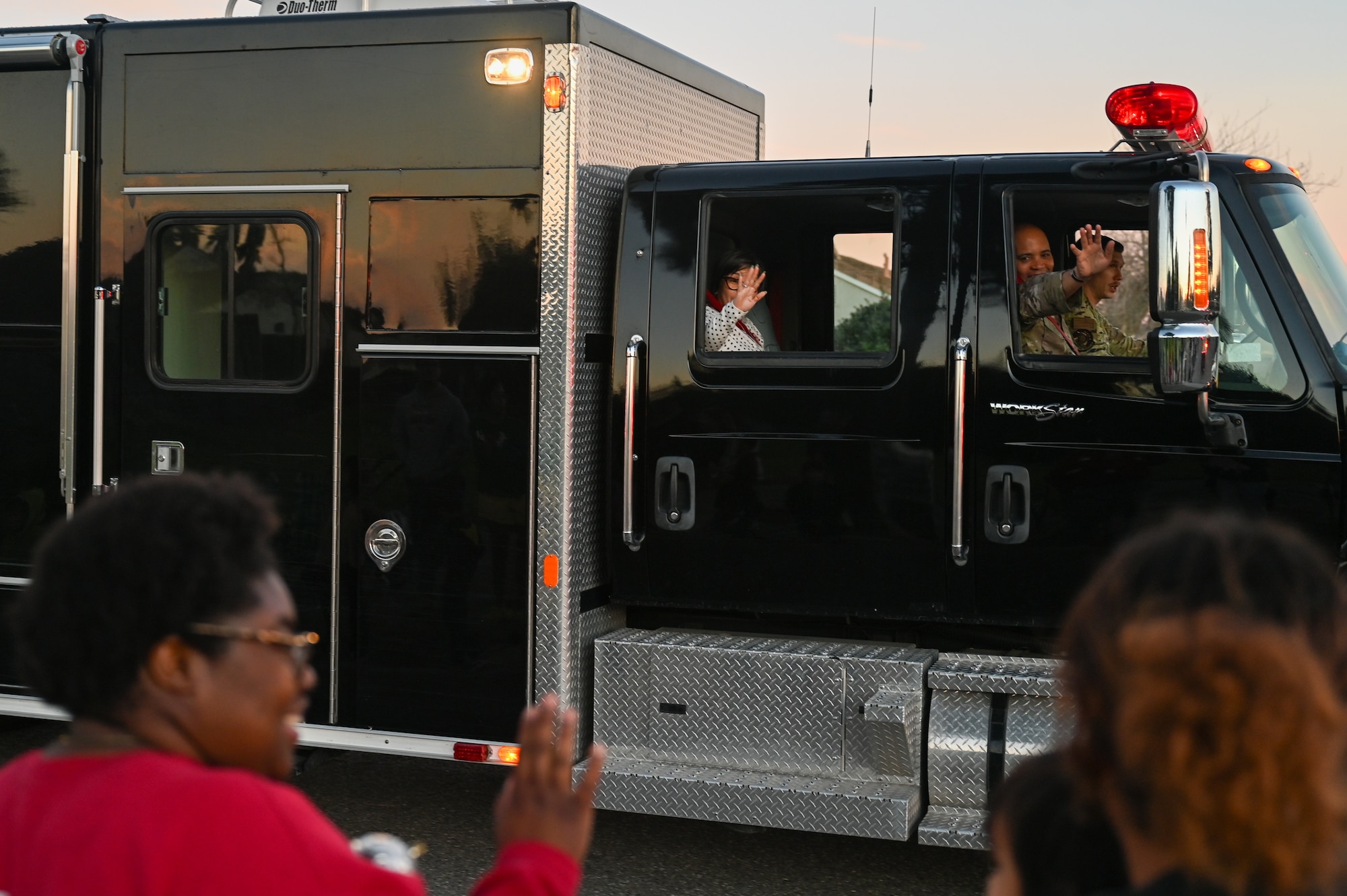 U.S. Air Force Chief Master Sgt. Malcolm Summers II, Space Launch Delta 30 senior enlisted airman, waves to the 2025 Holiday Parade crowd. He is inside a truck passing by the crowd.