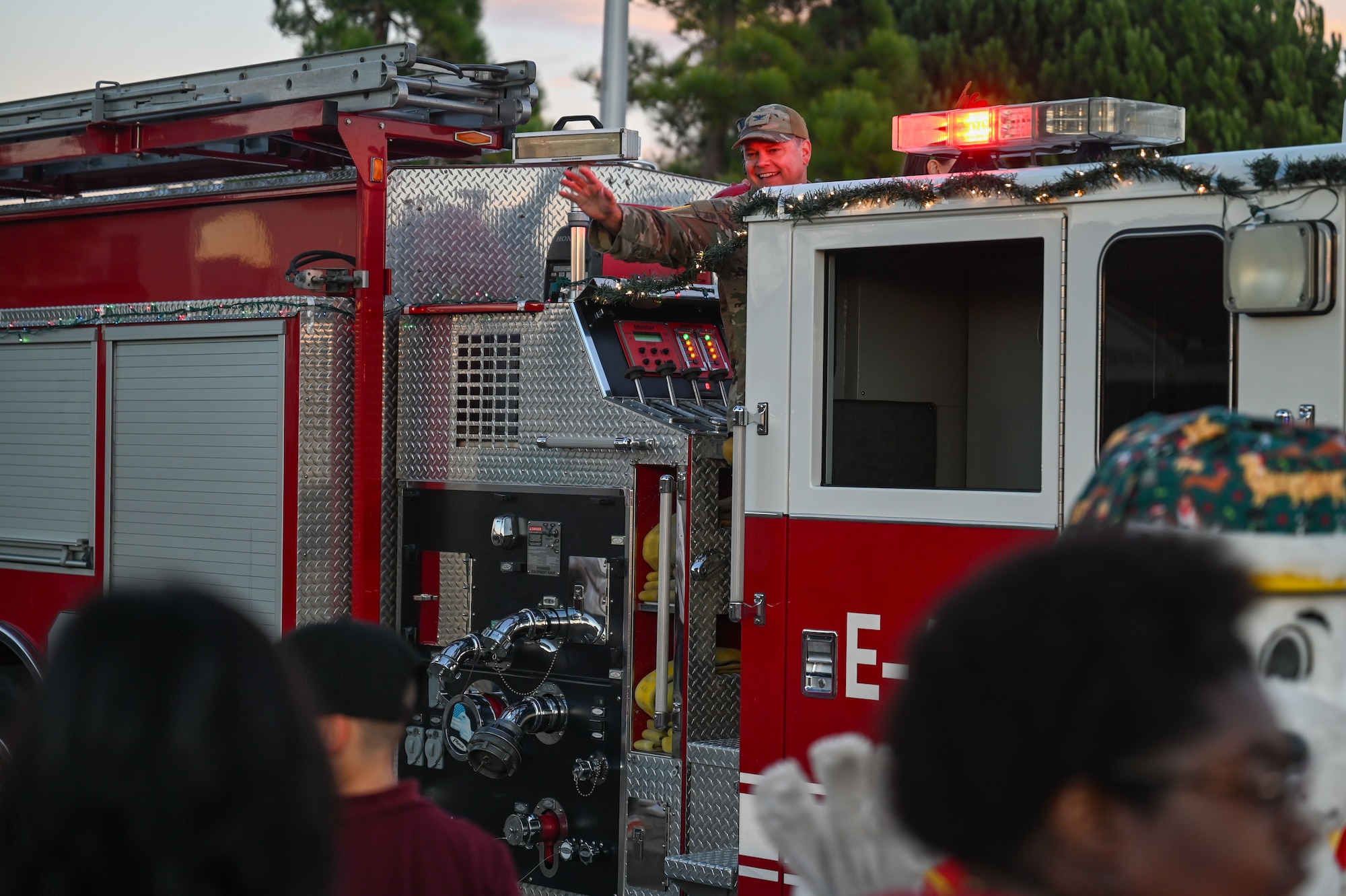 U.S. Space Force Col. James T. Horne III, Space Launch Delta 30 commander, waves to a crowd. He is on a firetruck passing by.
