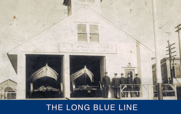 A July 1906 photograph showing the original boathouse and single bay entrance door for surfboat storage. The person standing second from the right is Keeper Thomas Ross, with other men that served in the initial station crew. (University of Washington digital archive)