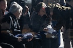 man in military uniform passing folded flag to crying mother.