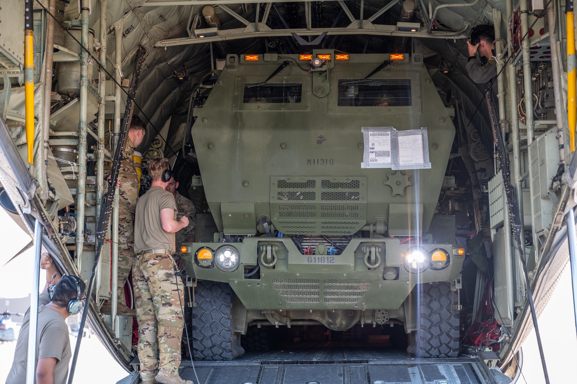 Airmen stand in the back of a C-130J