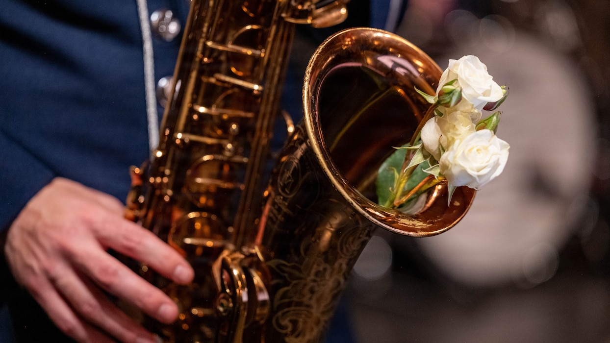 Flowers rest in a saxophone while an Airman plays it