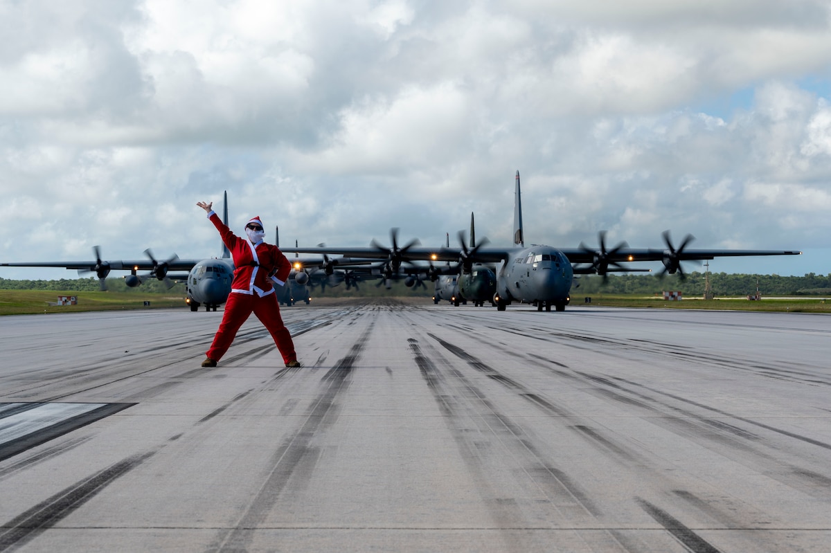 U.S. Air Force Lt. Col. Sara Wofford, 36th Airlift Squadron director of operations, stands before a formation of C-130J Super Hercules and C-130H Hercules aircraft from the U.S, Japan and Republic of Korea air forces participating in an elephant walk during Operation Christmas Drop 2025 at Andersen Air Force Base, Guam, Dec. 13, 2025.
