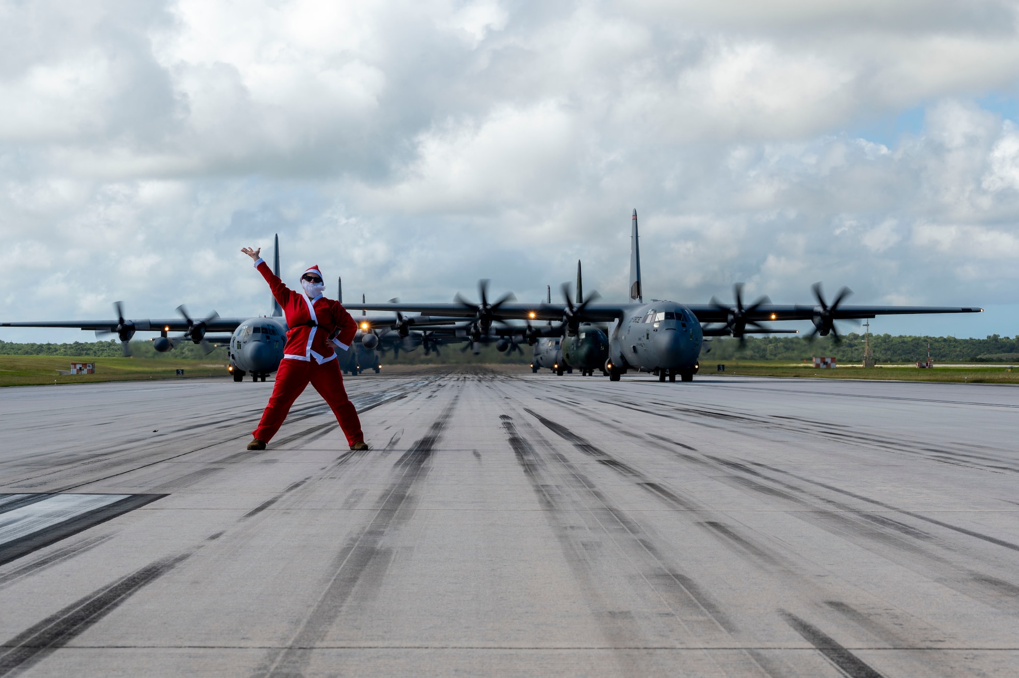 U.S. Air Force Lt. Col. Sara Wofford, 36th Airlift Squadron director of operations, stands before a formation of C-130J Super Hercules and C-130H Hercules aircraft from the U.S, Japan and Republic of Korea air forces participating in an elephant walk during Operation Christmas Drop 2025 at Andersen Air Force Base, Guam, Dec. 13, 2025.