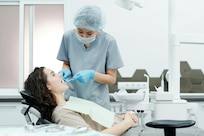 Dentist uses dental equipment on a patient in a white room
