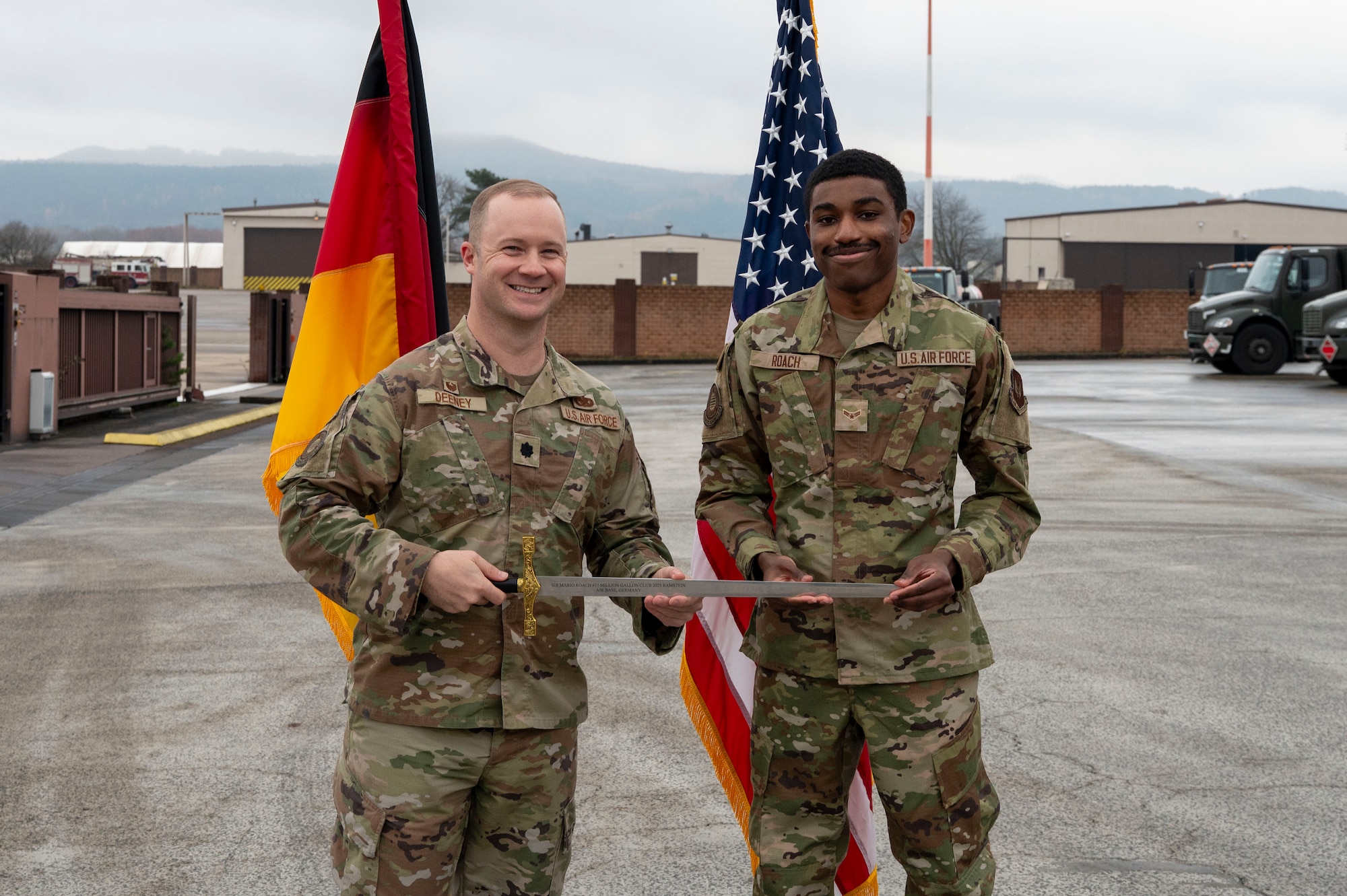 U.S. Air Force Lt. Col. Austin Deeney, 86th Logistics Readiness Squadron commander, and Airman 1st Class Mario Roach, 86th LRS fuels distribution operator, pose for a photo during a Knighting Ceremony at Ramstein Air Base, Germany, Dec. 5, 2025.
