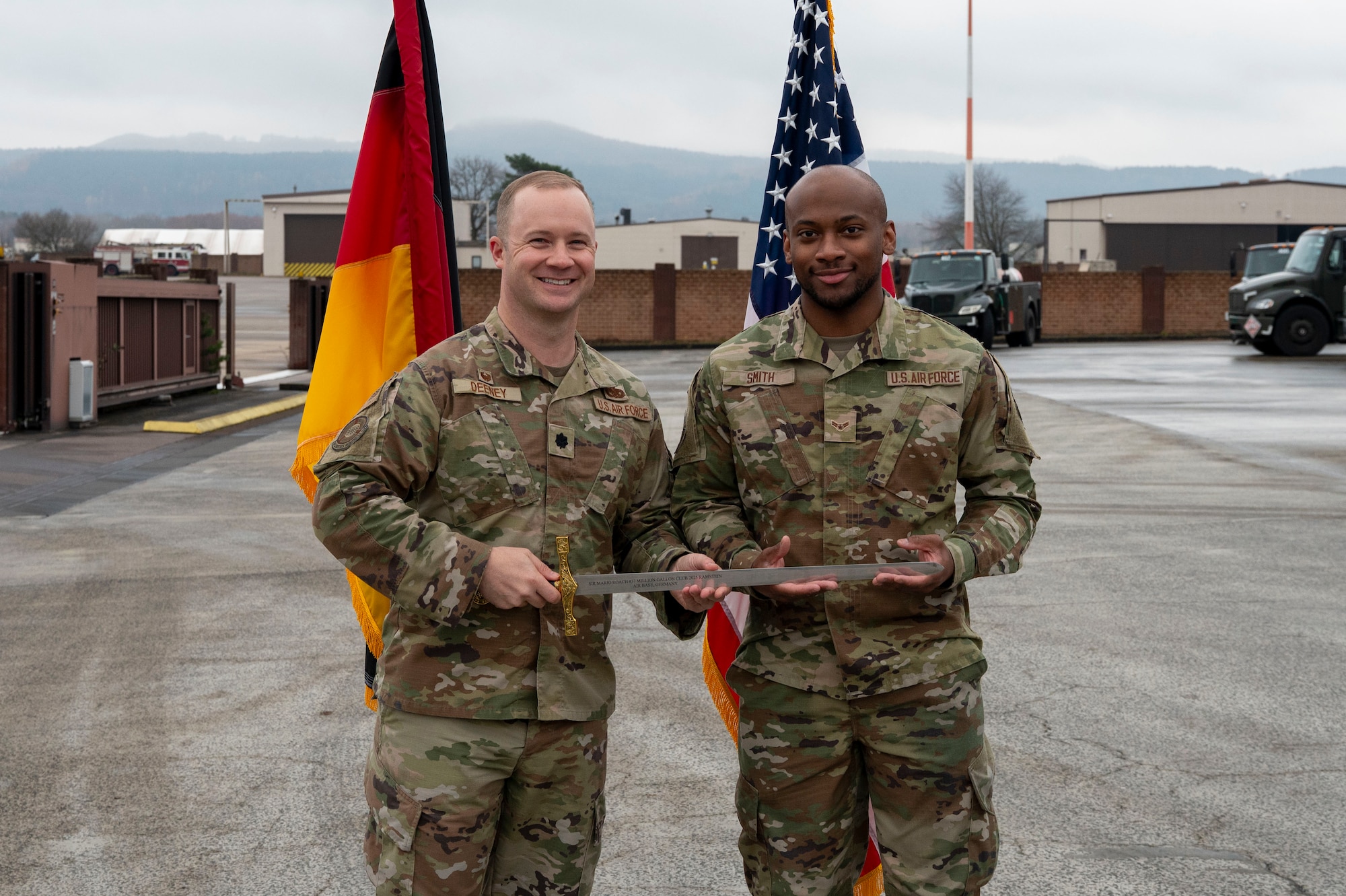 U.S. Air Force Lt. Col. Austin Deeney, 86th Logistics Readiness Squadron commander, and Airman 1st Class Tariq Smith, 86th LRS fuels distribution operator, pose for a photo during a Knighting Ceremony at Ramstein Air Base, Germany, Dec. 5, 2025.