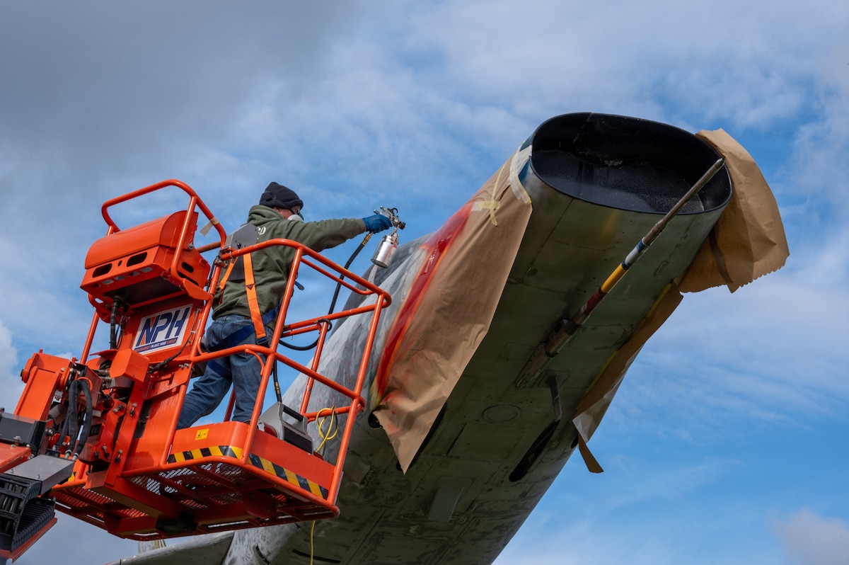 A man sprays paint on a plane.
