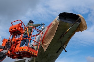 A man sprays paint on a plane.