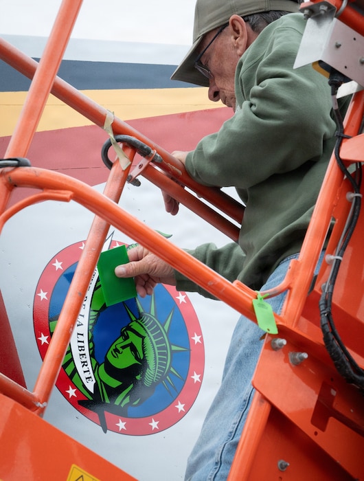 A man applies an emblem to a plane.