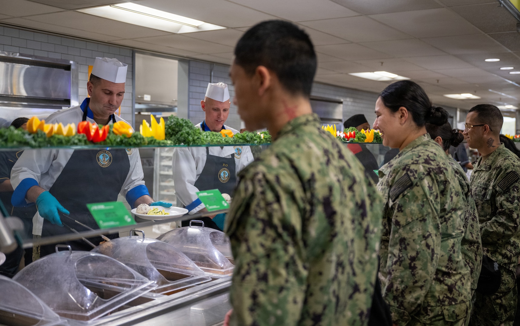 251211-N-CF730-1031 NAVAL BASE SAN DIEGO (Dec. 11, 2025) Cmdr. William R. Burkland, Executive Officer Naval Base San Diego, and Naval Base San Diego Command Master Chief Kristopher Freyberg serve various hot food items as part of the Christmas special meal at Naval Base San Diego, Dec. 11, 2025. Defense Logistics Agency Subsistence supply chain helps to keep morale high by giving servicemembers around the globe the smells and tastes of the December holidays.  (U.S. Navy photo by Interior Communications Electrician 2nd Class Ulrika Mendiola)