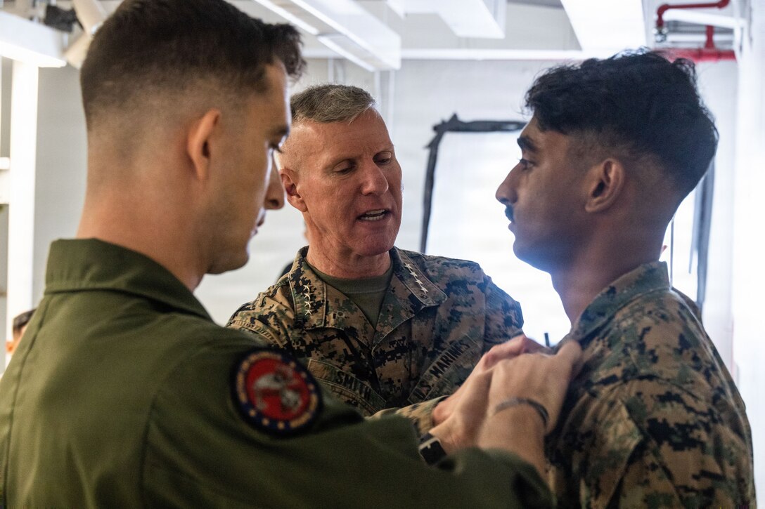 The 39th Commandant of the Marine Corps, Gen. Eric M. Smith, center, pins new chevrons on a a U.S. Marine with Marine Fighter Attack Squadron (VMFA) 225, U.S. Marine Corps Forces, South, after meritoriously promoting him to the rank of sergeant at Jose Aponte de la Torre Airport in Ceiba, Puerto Rico, Dec. 16, 2025. U.S. military forces are deployed to the Caribbean in support of the U.S. Southern Command mission, Department of War-directed operations, and the president’s priorities to disrupt illicit drug trafficking and protect the homeland. (U.S. Marine Corps photo)