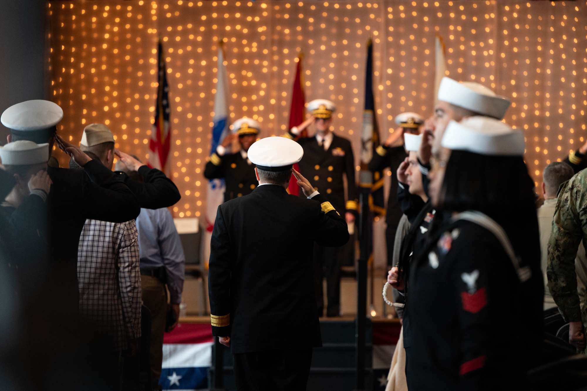U.S. Navy Rear Adm. Kevin Kennedy, Deputy Chief of Naval Personnel Command and Commander Navy Personnel Command, salutes Naval Consolidated Brigade Charleston leadership while walking towards the stage during the NCBC change of command ceremony.