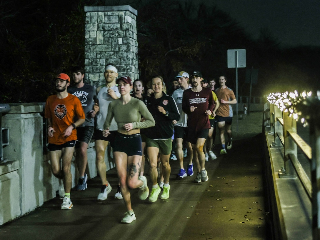 U.S. Marine Corps Capt. Grace Chow, the brand awareness officer with Marine Corps Recruiting Command, and Capt. Alexandra Elliott, Management Data Systems Officer with Headquarters Marine Corps, interact with coaches during a morning run in the U.S. Track & Field and Cross Country Coaches Association National Convention in Grapevine, Texas Dec. 17, 2025. The "Fit to Win: Morning Run at this year's convention is an opportunity to demonstrate grit and motivation; a commonality between student athletes and Marines.  (U.S. Marine Corps Photo by Lance Cpl. Abram Maestre)