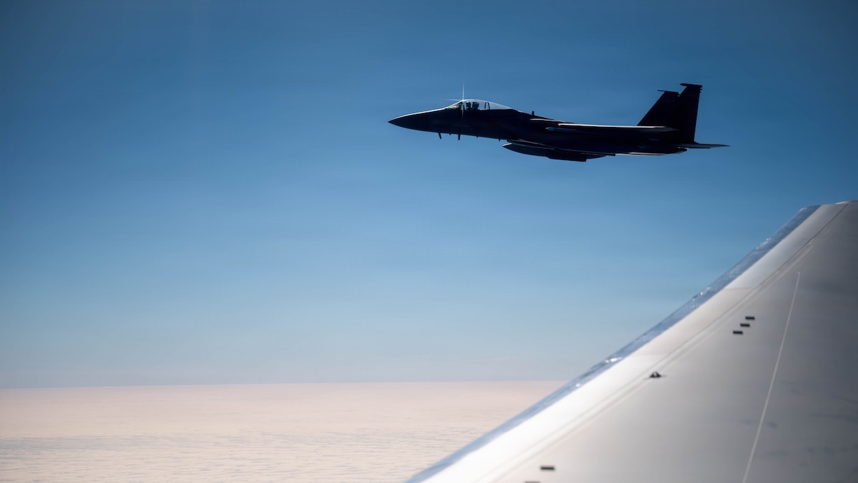 An aircraft flies with a wing in the foreground