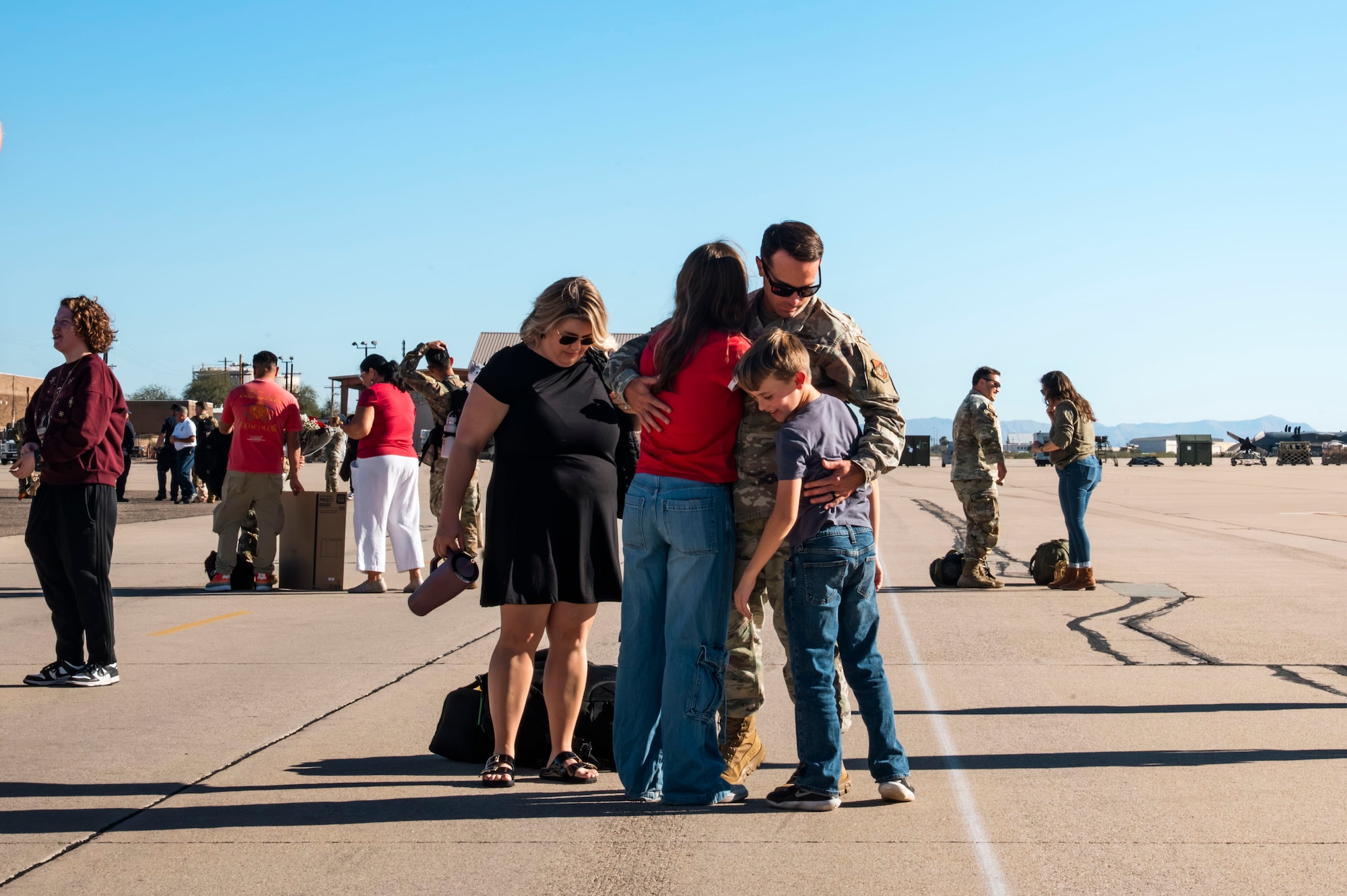 A U.S. Air Force Airman returns to his family after a deployment with the 11th Air Task Force at Davis-Monthan Air Force Base, Arizona, Dec. 17, 2025. Airmen returned home after completing a five-month deployment in the Republic of Korea, Saipan and Guam. (U.S. Air Force photo by Airman 1st Class Samantha Melecio)