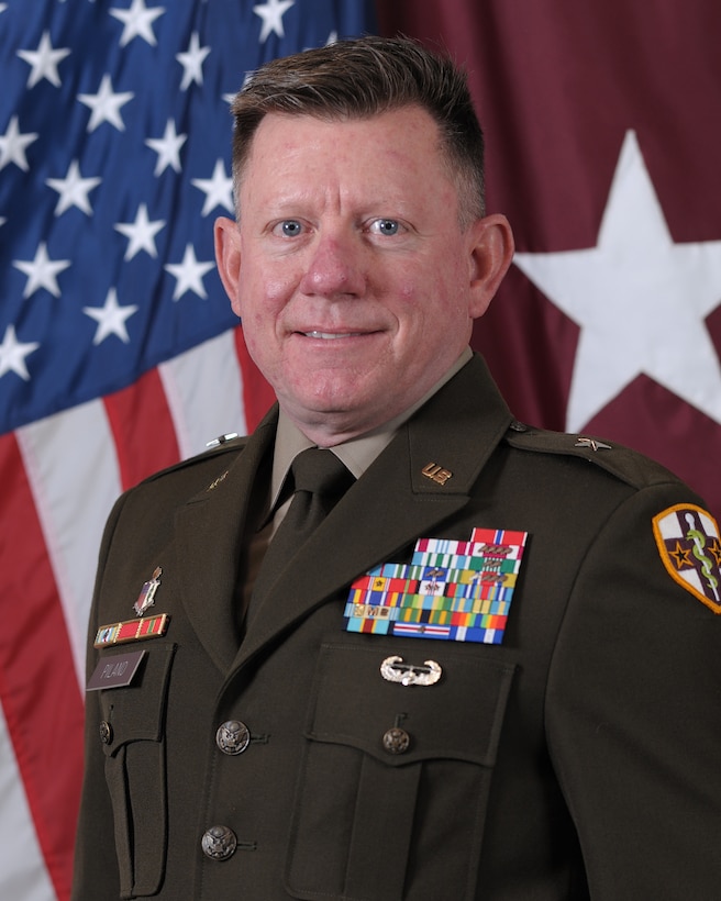 Image of Brig. Gen. Christopher Piland command photo in Army Green Service Uniform with U.S. flag and maroon one white star flag in background