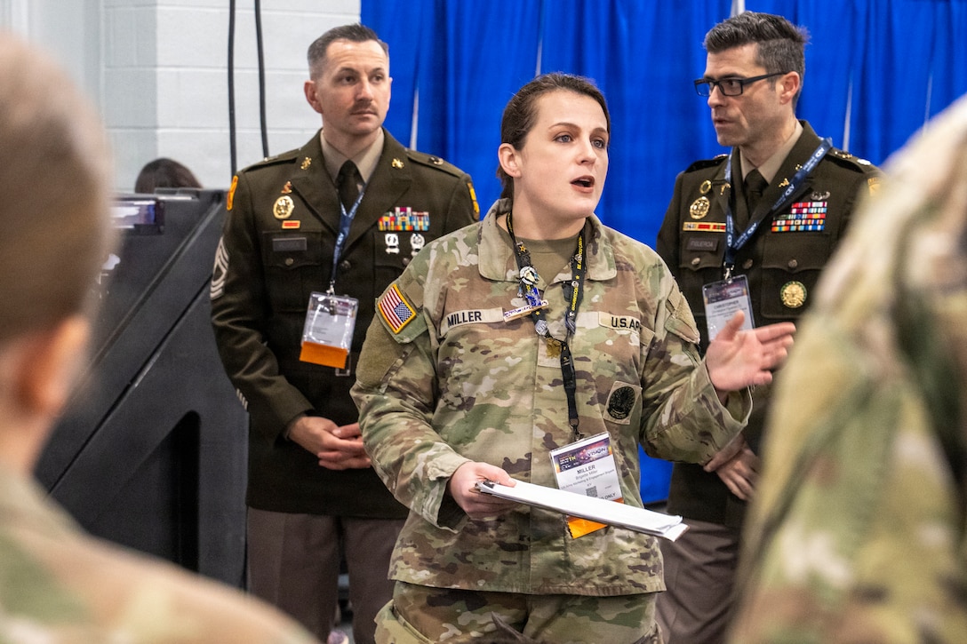 woman wearing u.s. army uniform standing in front of two men wearing u.s. army uniforms.