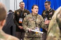 woman wearing u.s. army uniform standing in front of two men wearing u.s. army uniforms.
