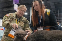 woman wearing u.s. army uniform demonstrates a dog mannequin to a women wearing business clothes.