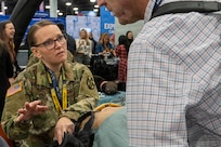 woman wearing u.s. army uniform talks with a man wearing business clothes.